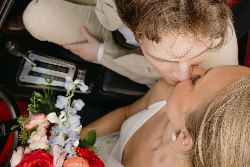 Couple share a kiss after their wedding in a vintage car parked in downtown Nashville, TN.