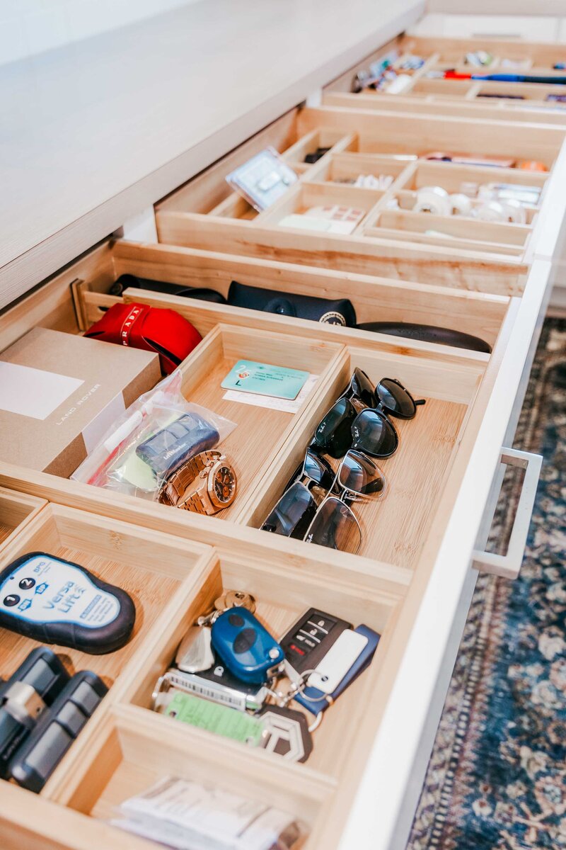 An open drawer showing organized glasses, keys and watches