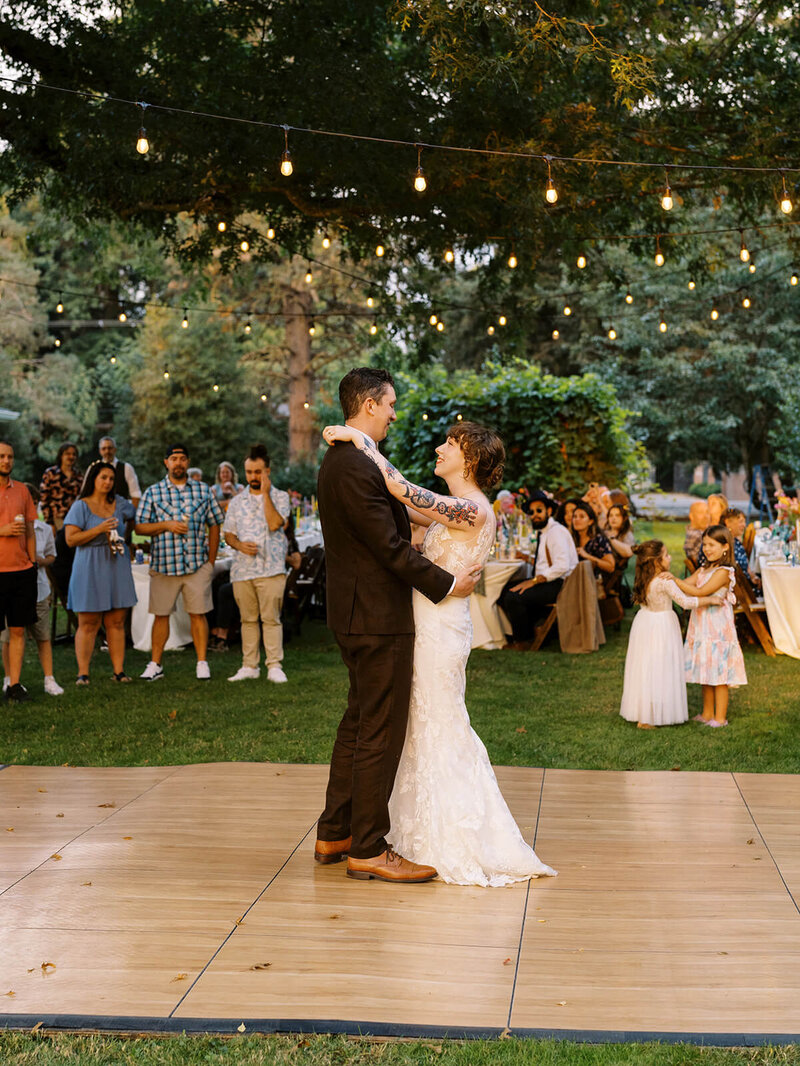 A bride and groom dancing with guests in the background, representing an example of work from Heather's wedding portfolio. 