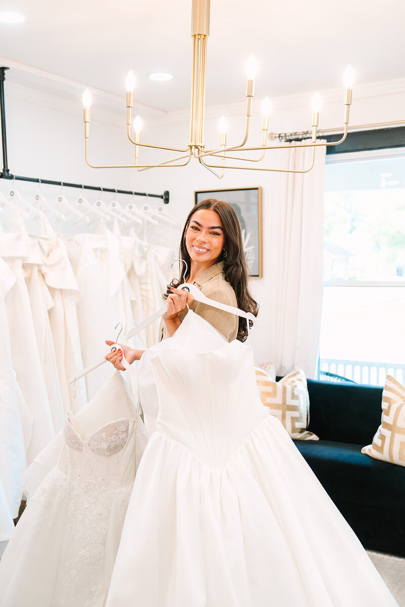 bridal stylist smiling among dresses