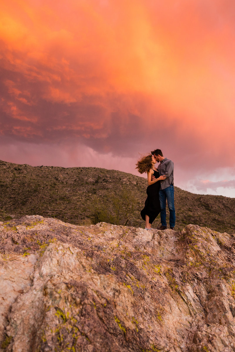 An engaged couple kisses in Saguaro  National Park during an epic sunset.