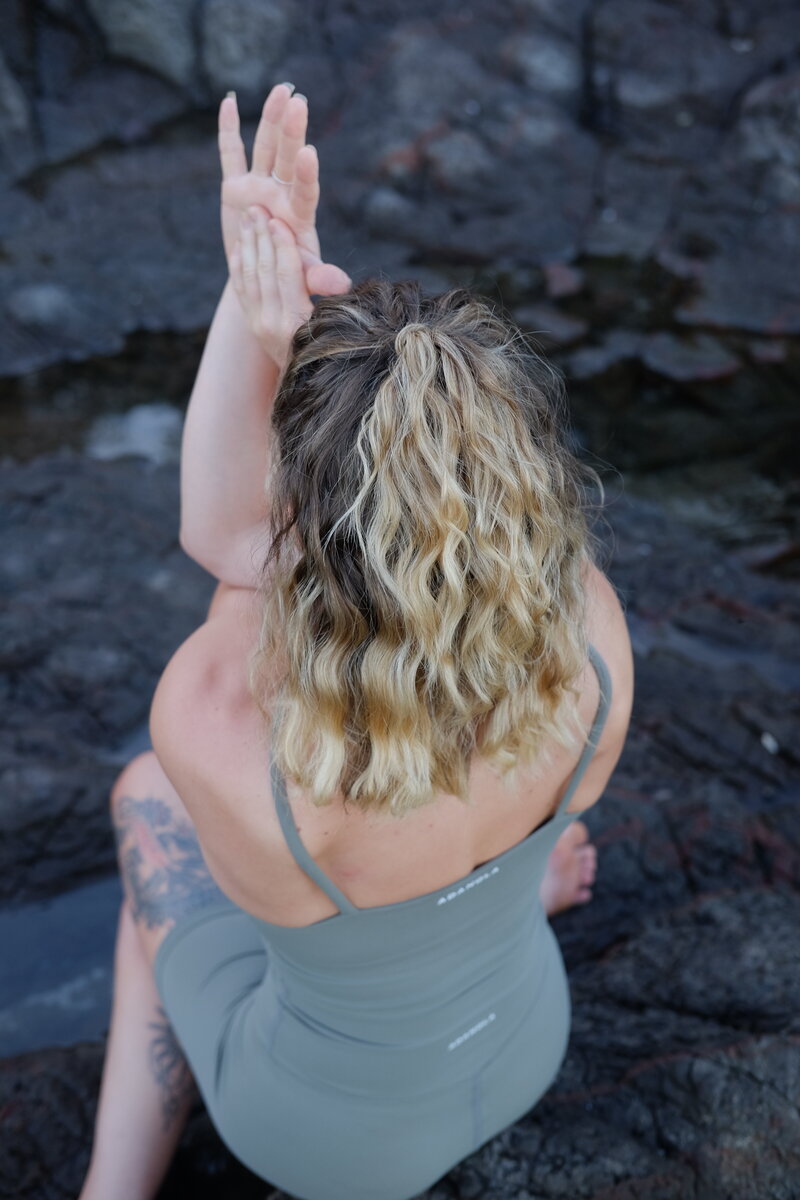 yoga woman in twisted arms pose with blonde beach wavey hair