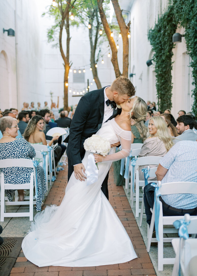 bride and groom kissing as they exit wedding