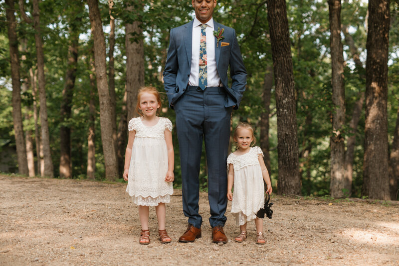 Groom looks down at flower girls  at wedding