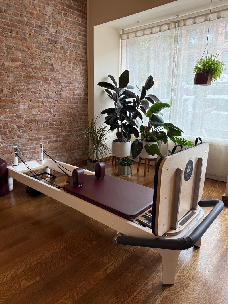 A mom holding her baby while laying on the reformer to a Baby and Me Pilates class in Park Slope, Brooklyn