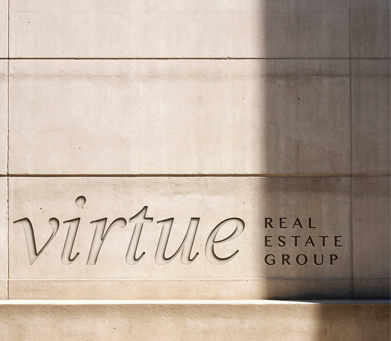 Virtue Real Estate Group logo engraved on a concrete wall, showcasing a sophisticated and modern brand identity.