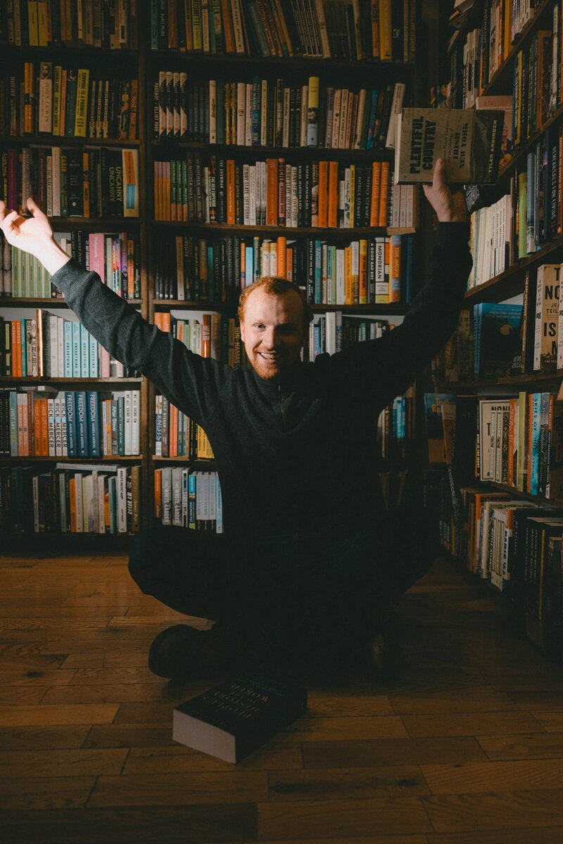 Wedding Photographer Connor Esau smiling and holding up a book at a bookstore in Calgary