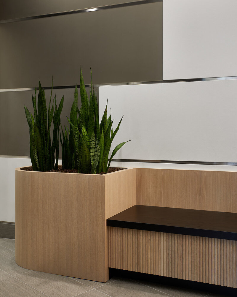 An indoor planter next to a bench with fluted wood panels