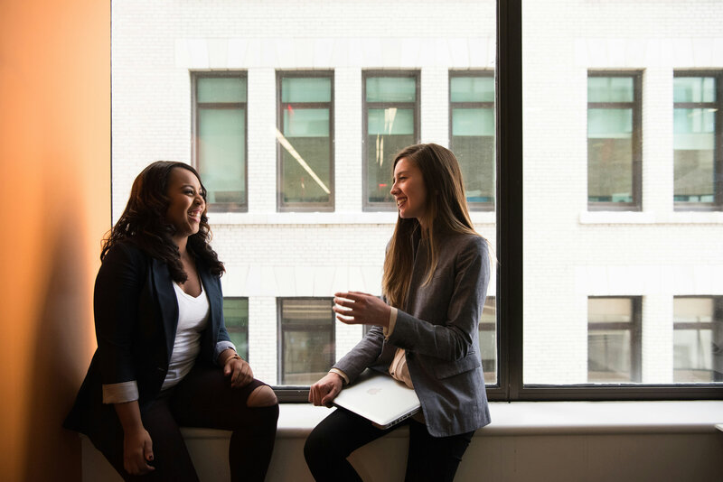 Two women having a conversation on a window sill.