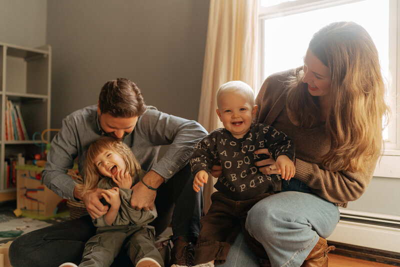 couple smiling with their two kids during at home family photoshoot captured by NYC family photographer Elsie Goodman 
