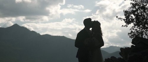 A silhouetted couple embrace in front of a mountain
