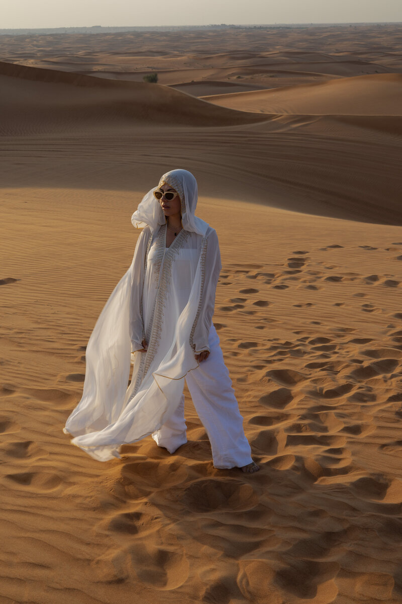 Female traveler walking barefoot on golden desert dunes