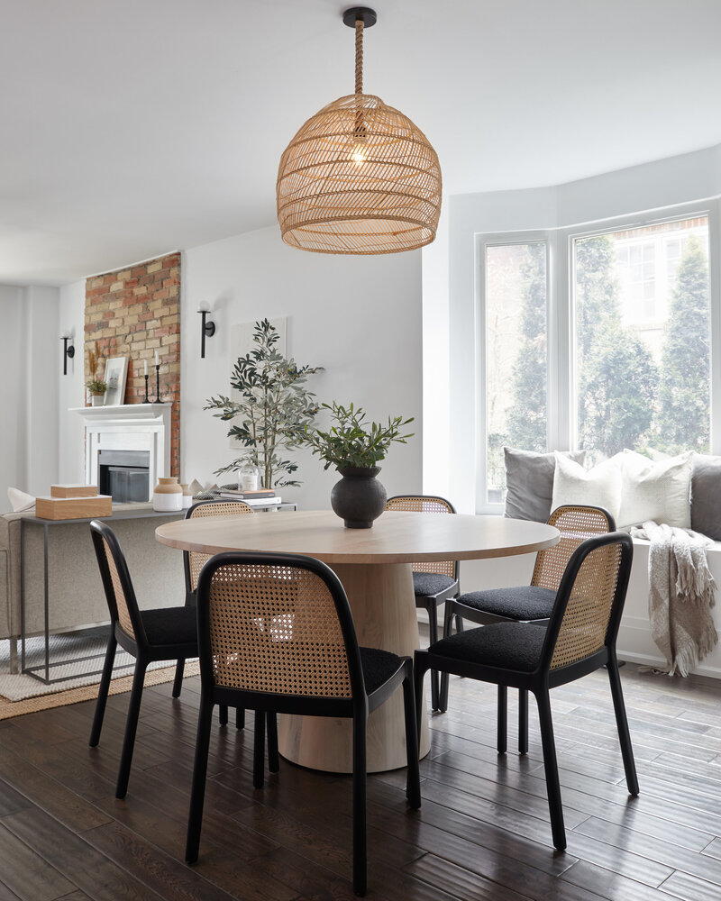 A before and after transformation of a dining room table from an outdated, blocky set to a elegant modern set featuring a round wood table, a rattan chair set, and potted plant