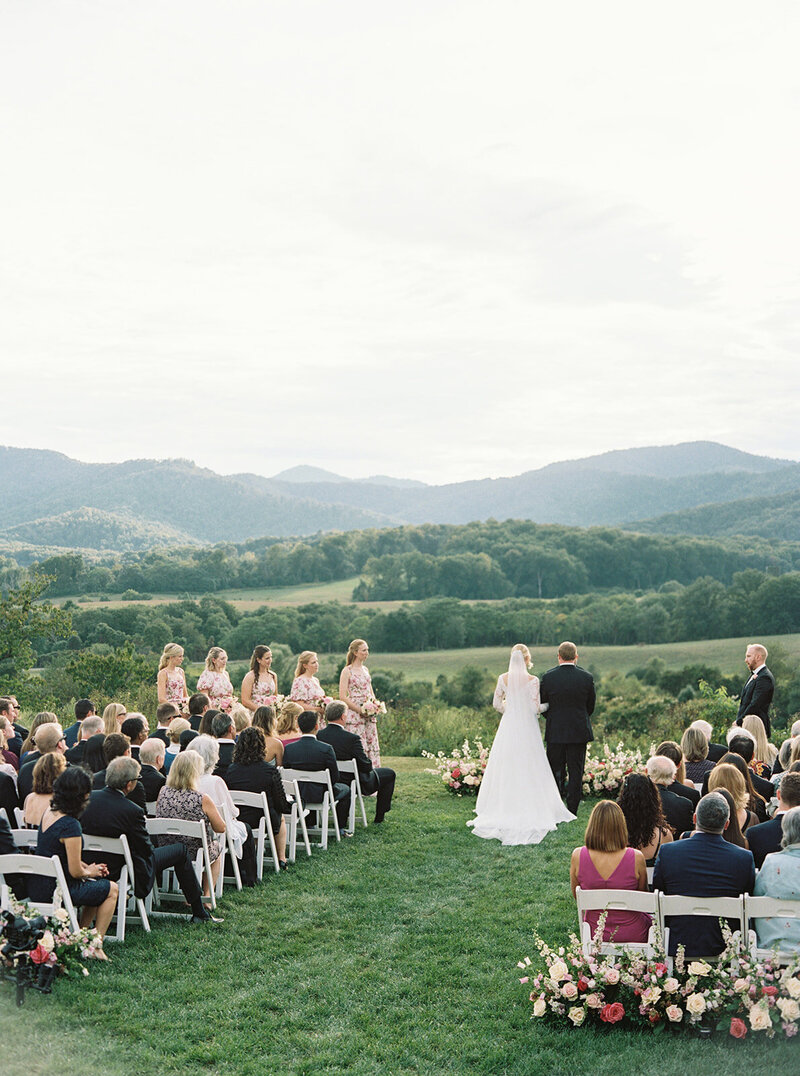 Candid fine art wedding portrait of bride and groom dancing in an open field with overcast skies