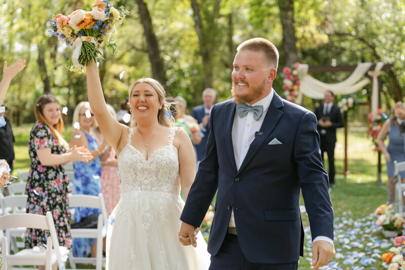 Sarasota wedding photos of bride and groom walking down the aisle together after their springtime ceremony in a wooded area. 