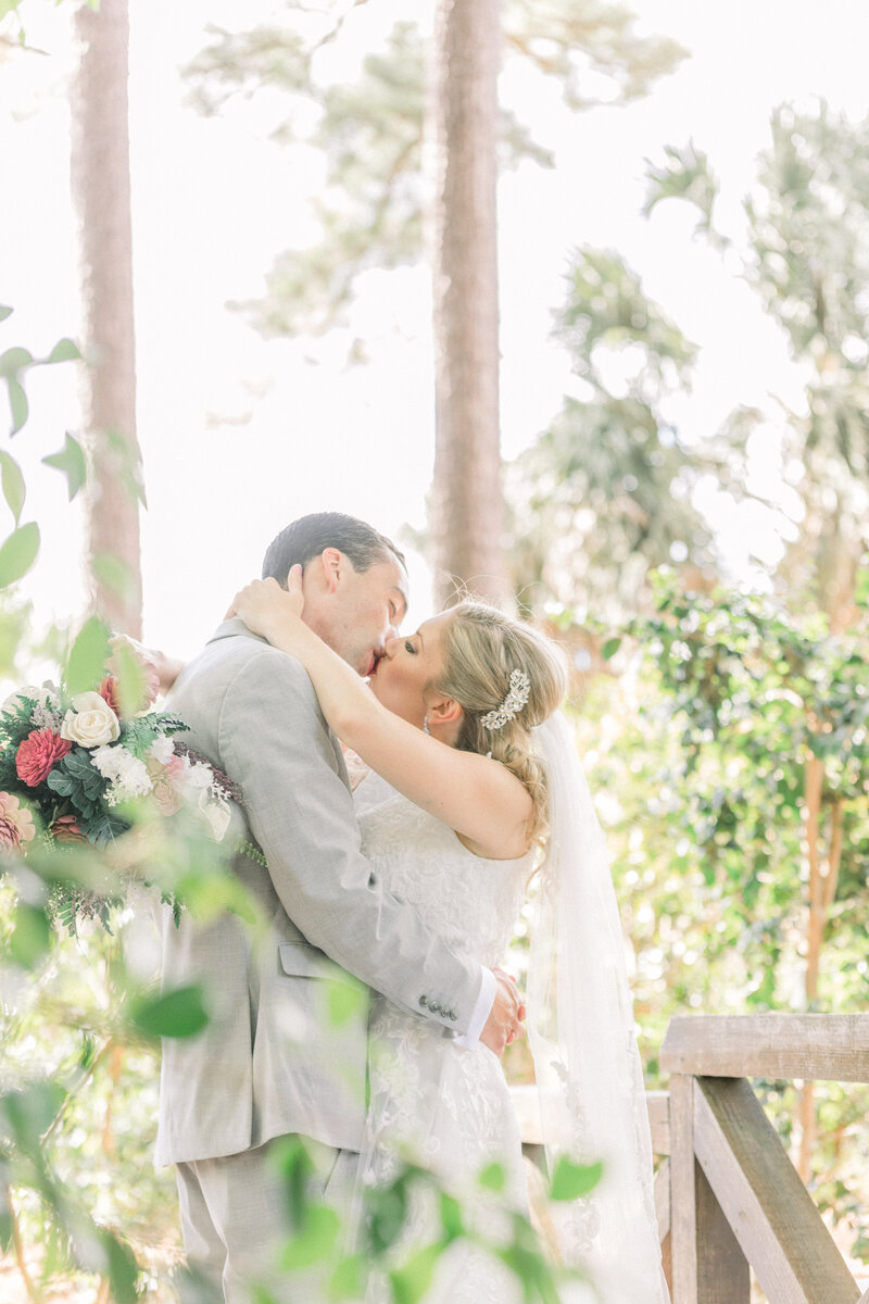 bride and groom kissing through the trees