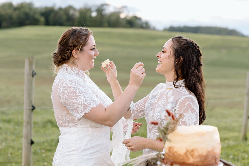 Two brides feeding each other cake during their elopement.
