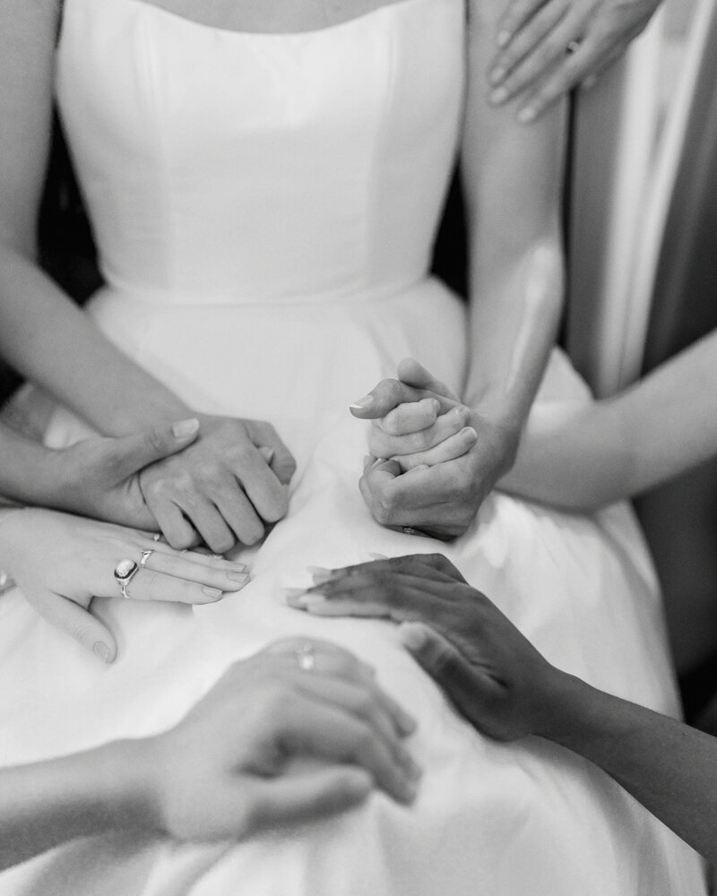 The bride stands with hands laid on her in prayer before the ceremony, surrounded by loved ones in a meaningful Christian wedding moment, captured by Jessica Leigh Photography.