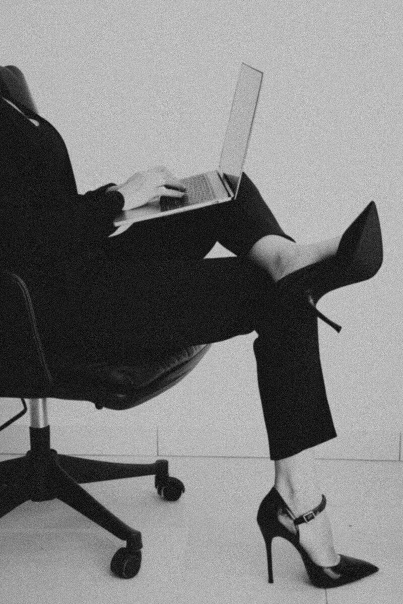 A black and white photo of a woman having an opened laptop on her legs