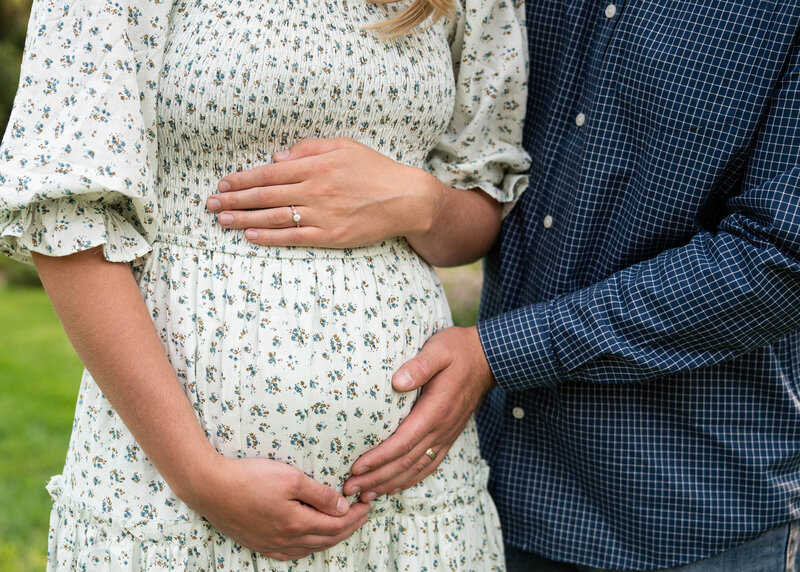 Soon-to-be parents hold the woman's baby bump during their pregnancy announcement photo shoot.