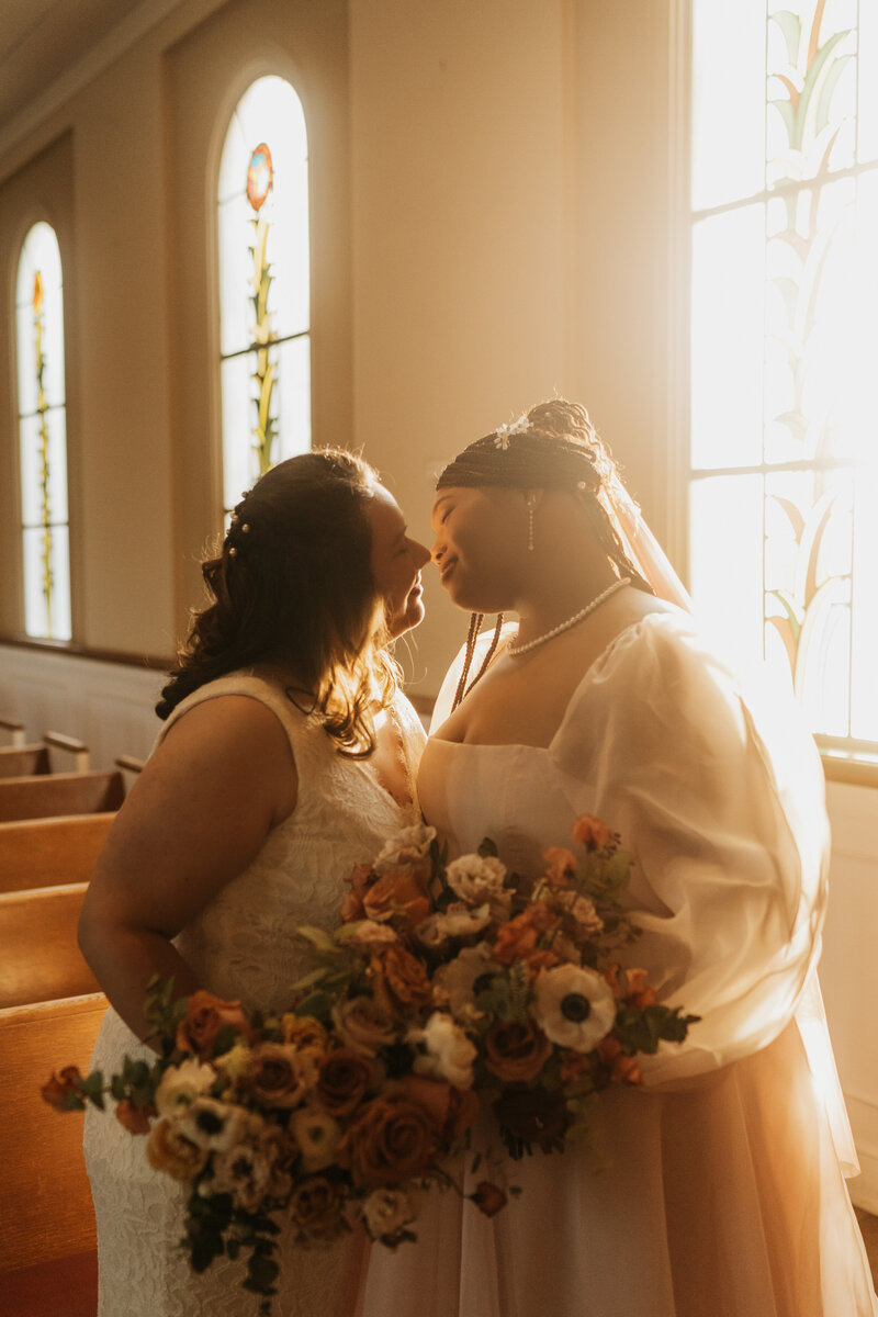 A newlywed couple standing in a church leaning in to kiss 