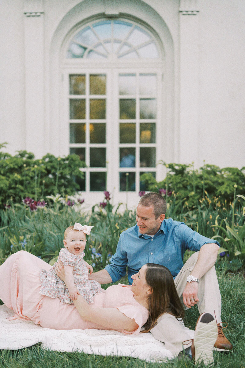 family snuggling on the ground with little girl