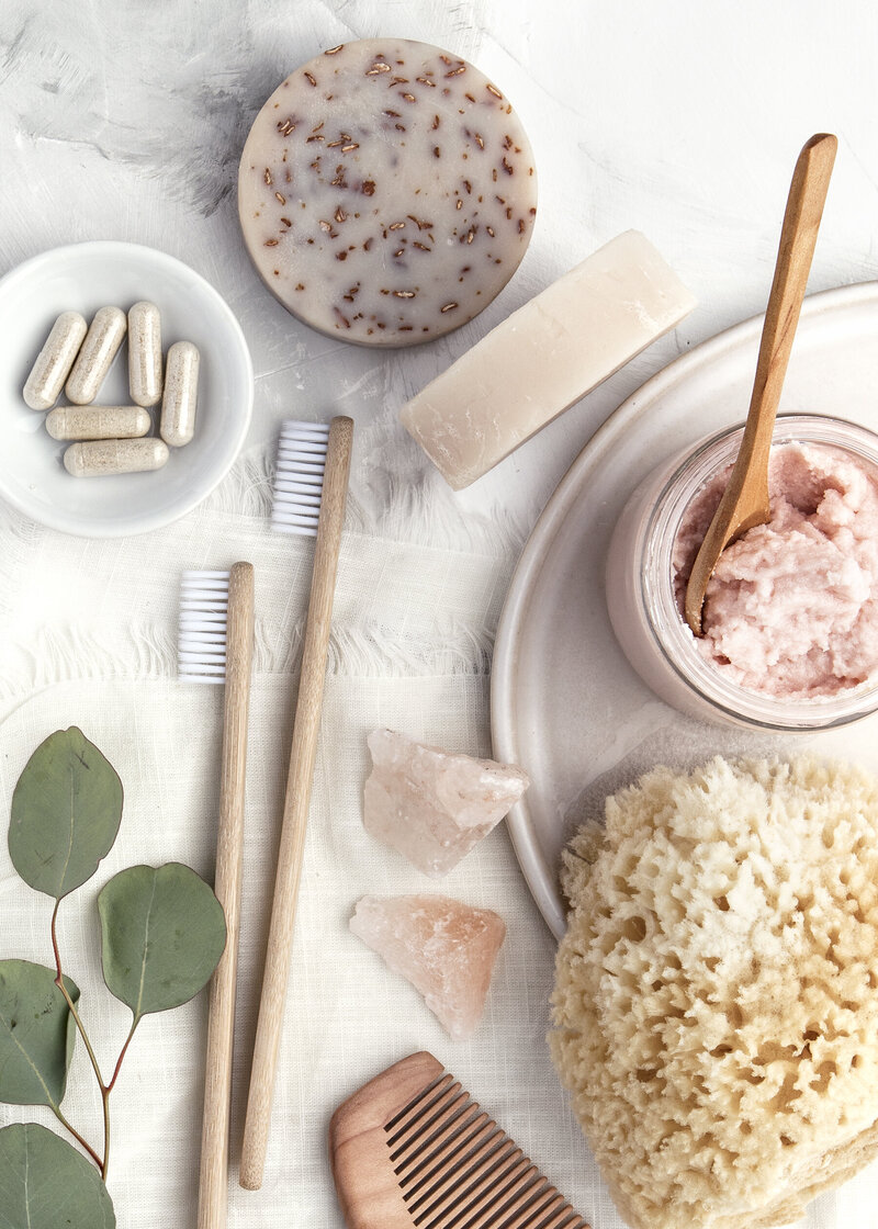supplements, green leaves, soap, crystals, wooden toothbrushes, pink scrub, and sea sponge