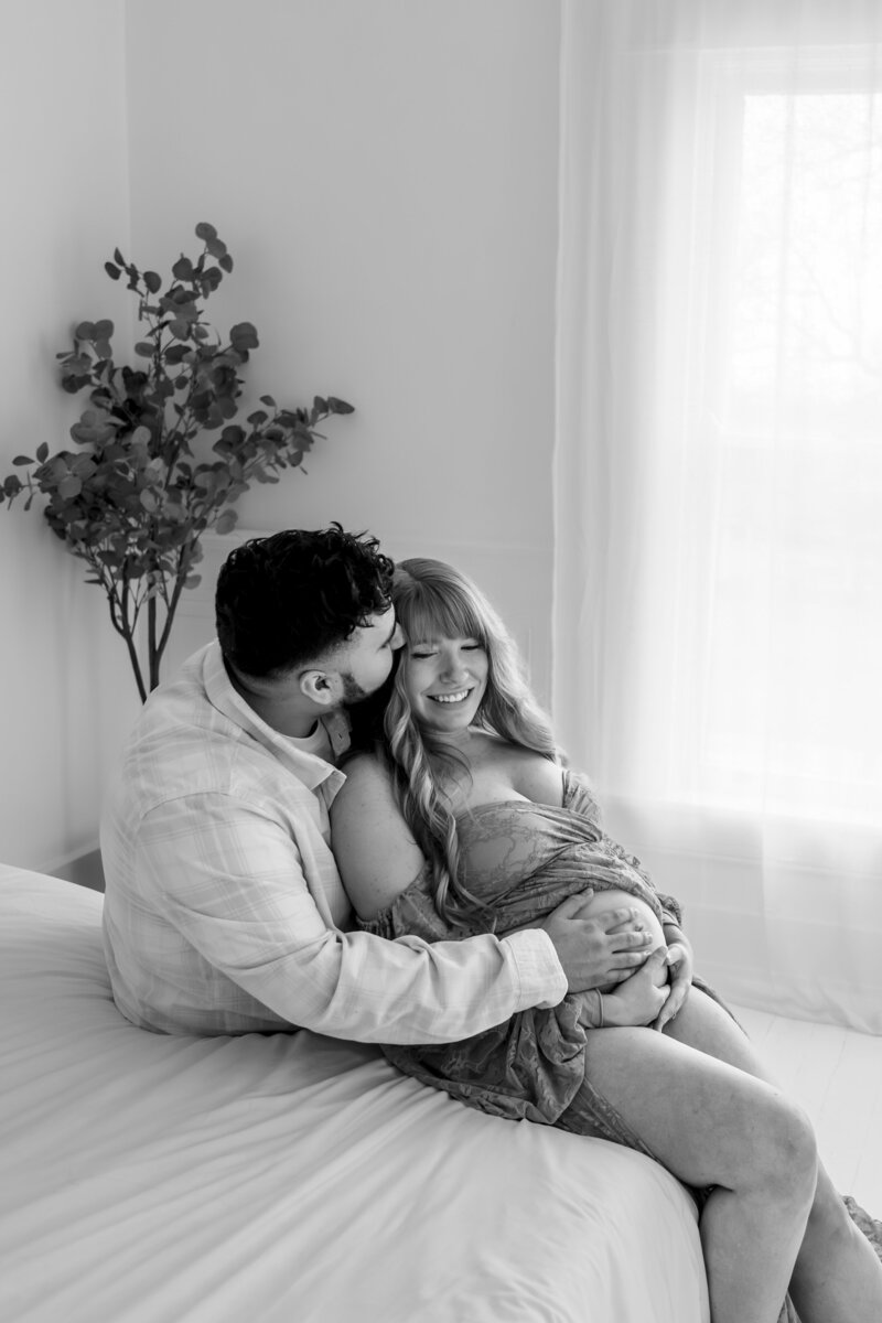 Expecting couple posing together in a studio setting, sharing a loving and intimate moment.