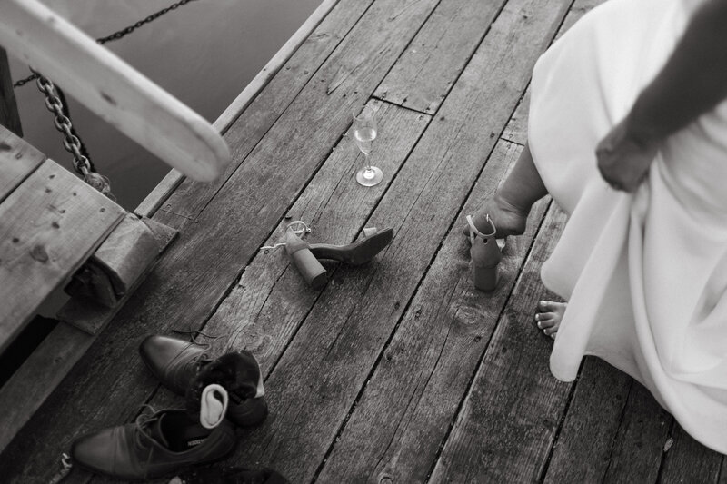 Bride kicking off her heals at the edge of a dock.