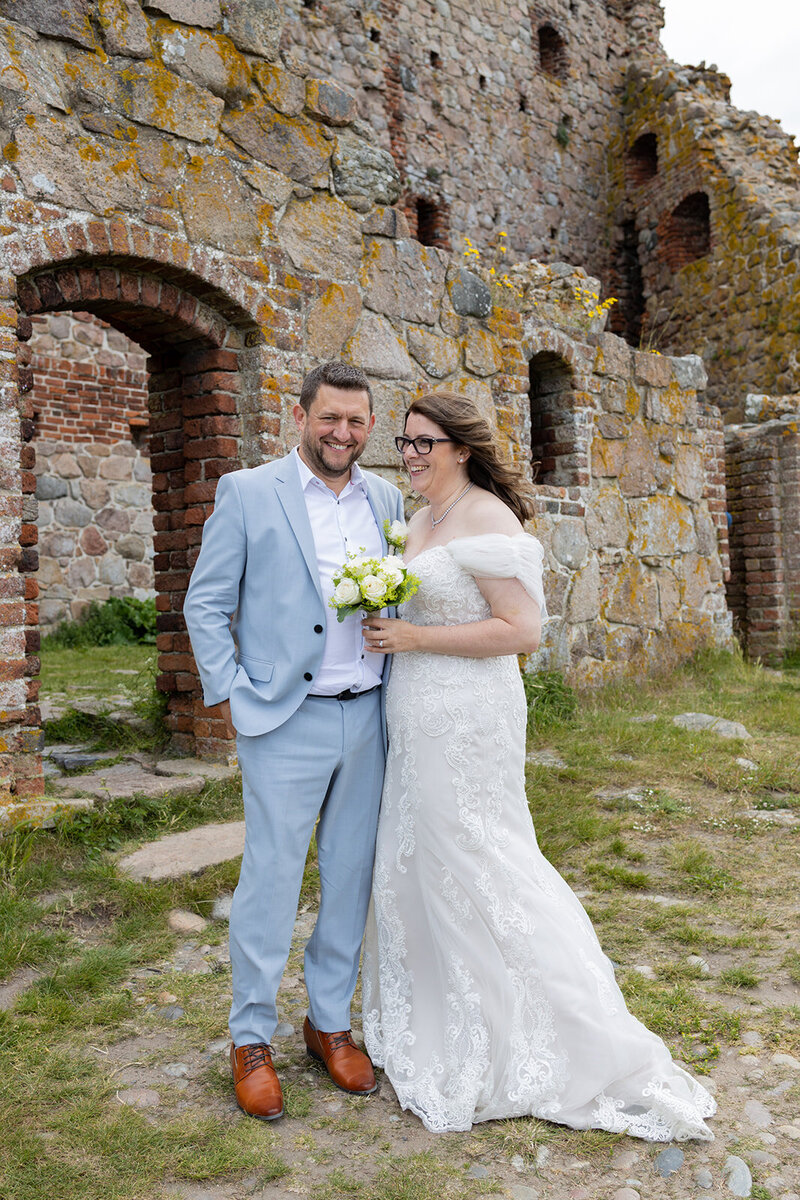 Couple posing in Hammershus ruins where they get married abroad in Danish island
