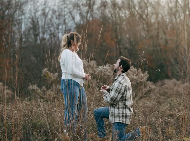 A groom to be proposes in a field captured by a Michigan wedding photographer