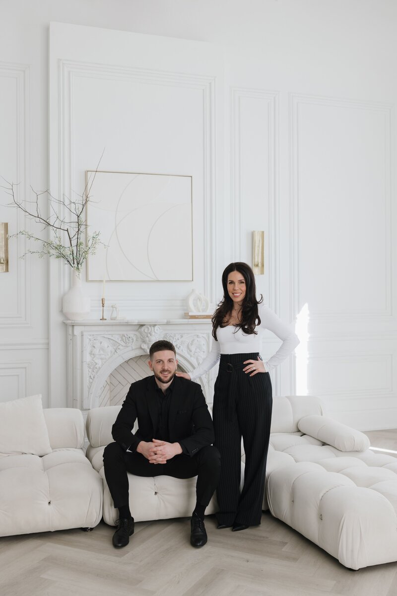 Steven and Caroline in black outfits on a white couch