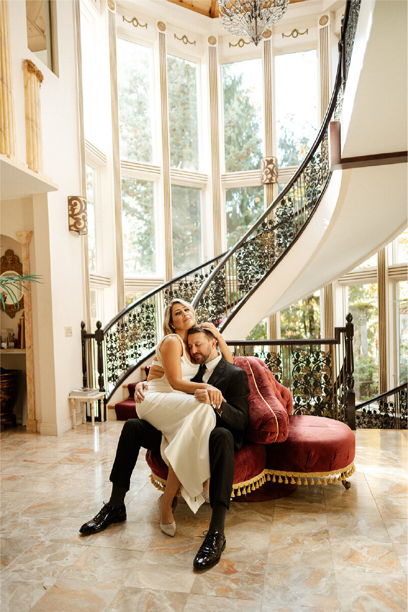 bride and groom cuddling on fancy couch