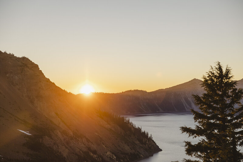 The sunset over a mountain range with a lake 