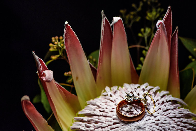 A detail of the wedding rings laying on the bride's bouquet of flowers.