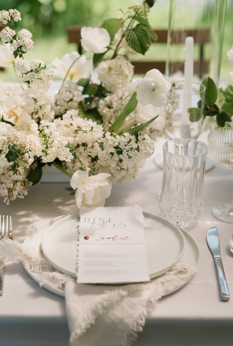A menu on top of a wedding guest plate, demonstrating custom calligraphy by Life in Letters
