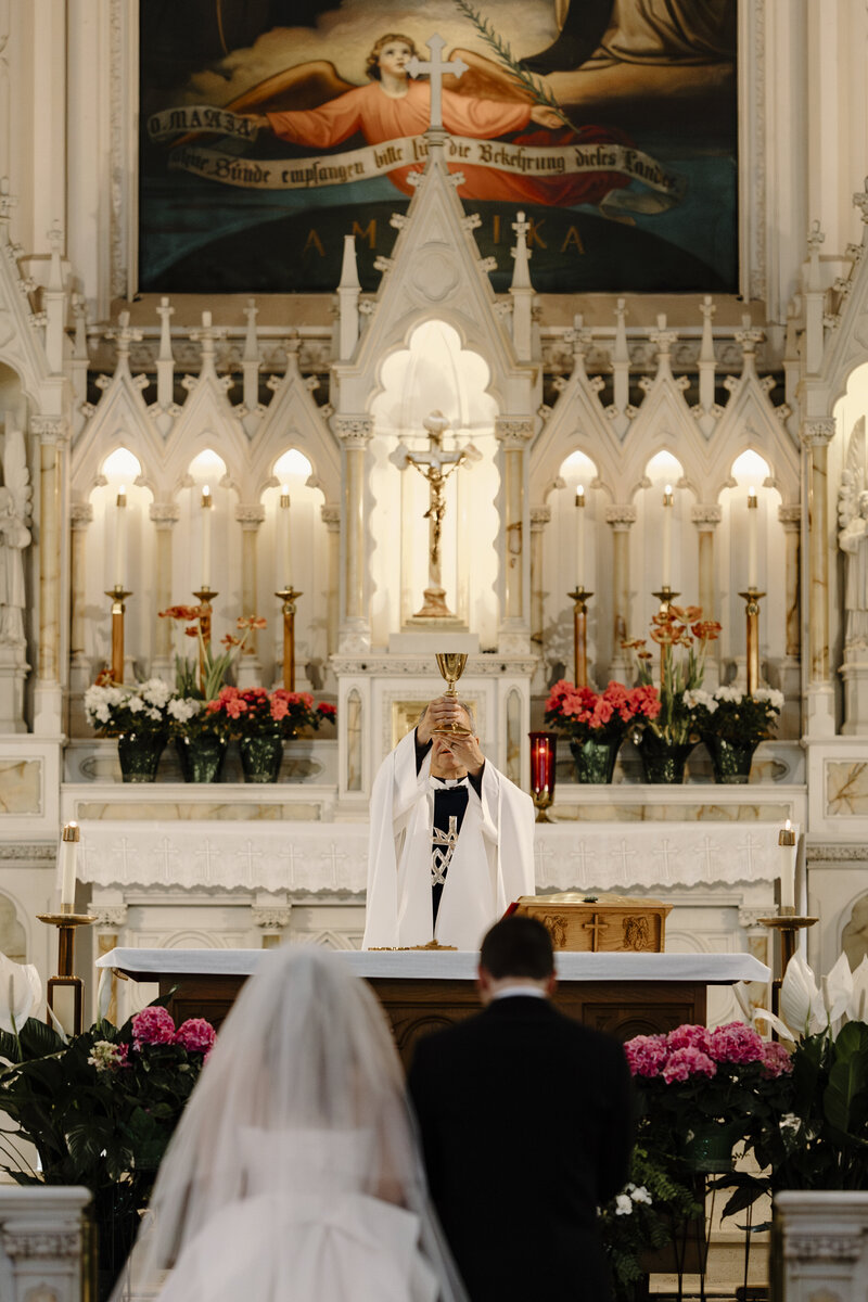 A BRIDE AND GROOM IN FRONT OF THE ALTAR AT HOLY CROSS CHURCH CINCINNATI
