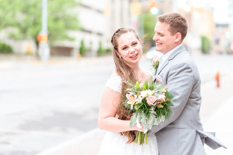 Bride laughs while groom looks on.