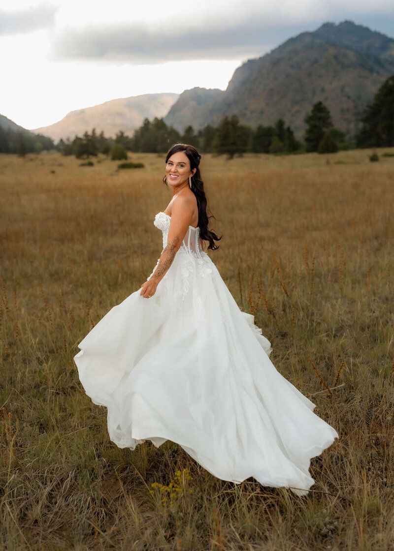 Bride twirling in her flowing white wedding gown in a grassy field