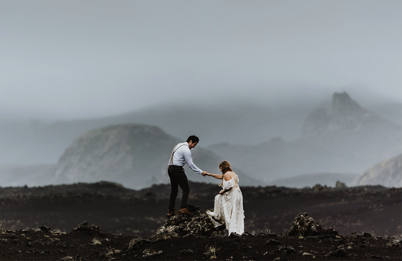 Married couple is climbing up on a rock in the middle of the dramatic highlands of Iceland