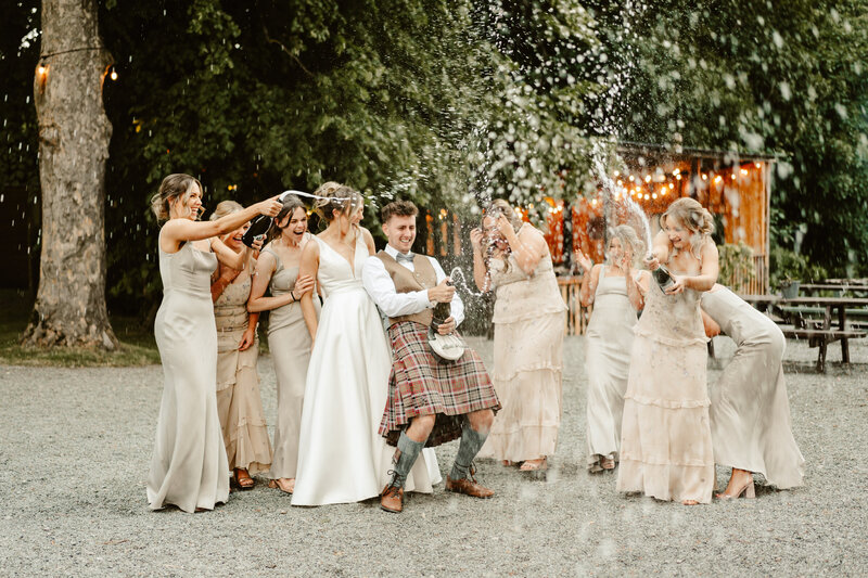 bride and groom laughing as thy walk towards camera with loch and hills in background natural alternative wedding photographer scotland