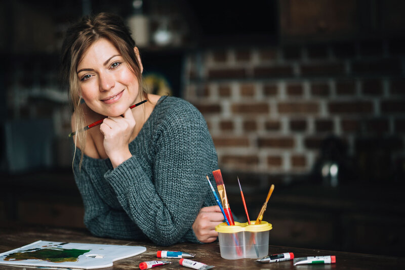 Woman smiling while holding a paint brush