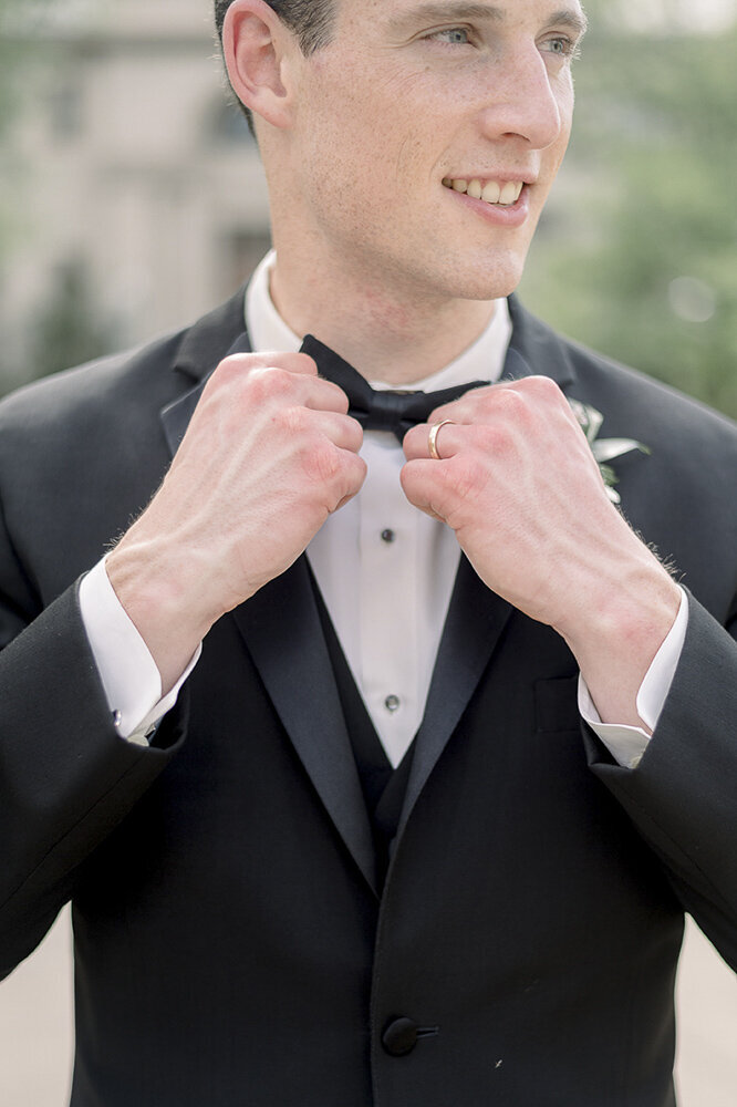 a groom adjusting his bow tie