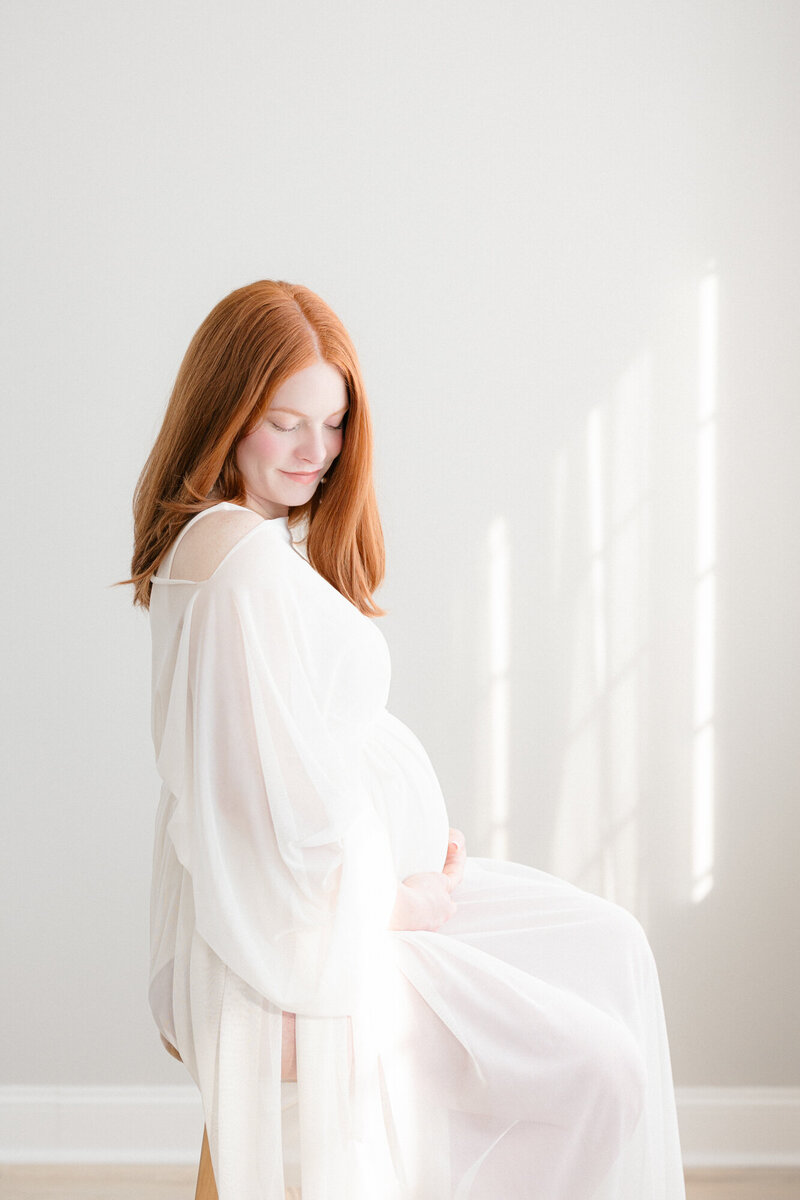 Expecting mom wearing a white chiffon dress in a bright louisville maternity photography studio