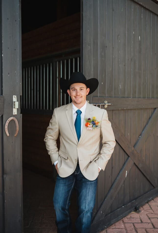 Groom by barn doors at Hanging H wedding venue