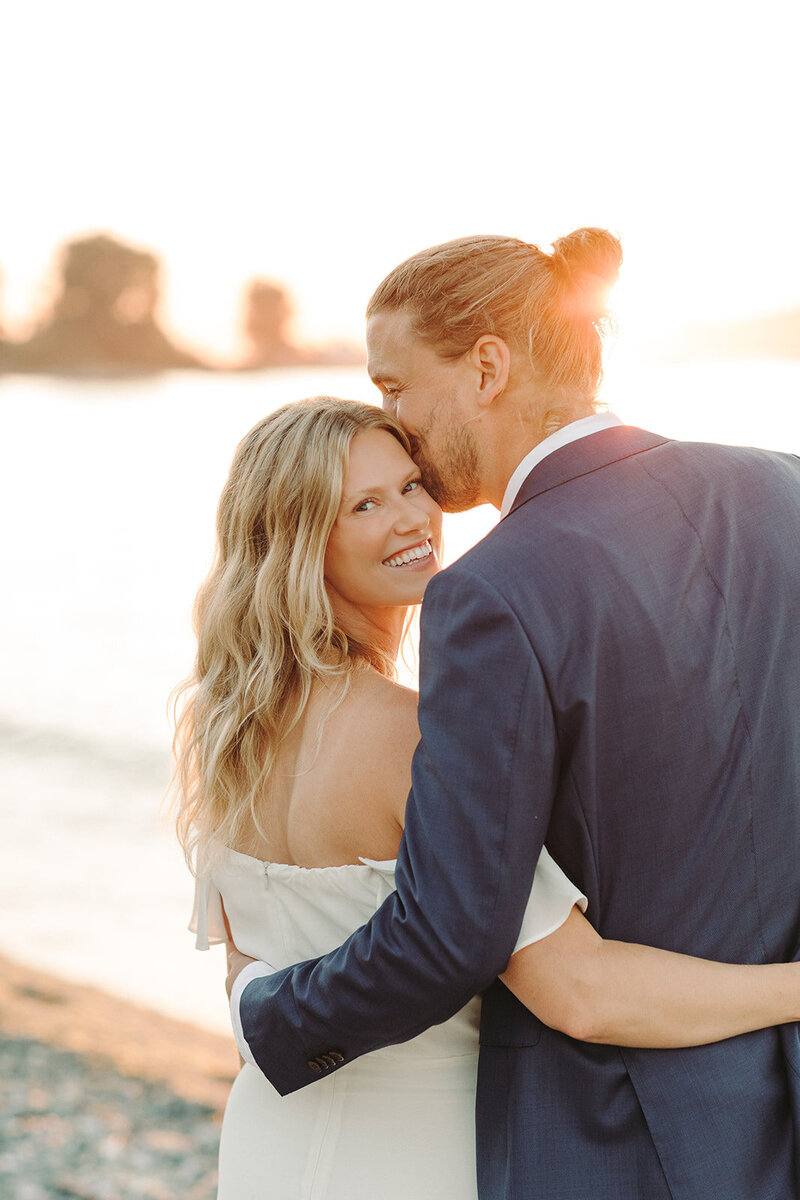 Wedding Photographers in Salt Lake capture groom kissing bride at sunset after boho wedding
