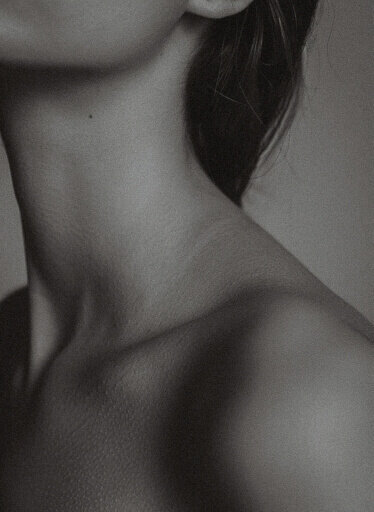 Minimalistic black-and-white image of a woman's neck and collarbone, symbolizing somatic awareness and grace.