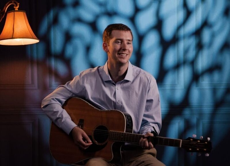 A person sitting down playing guitar  