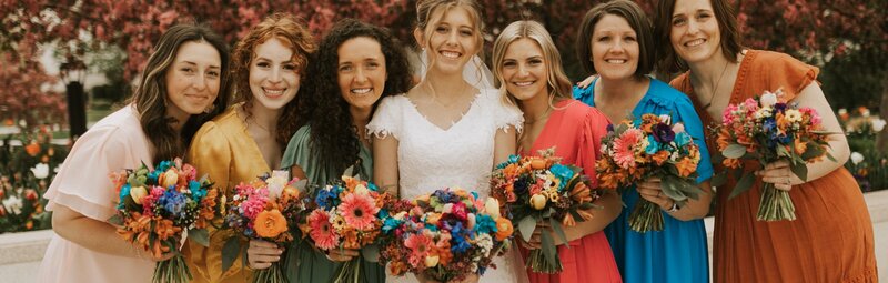 bride with all her bridesmaids holding bright and beautiful bouquets made by Buds Blooms and Blossoms 