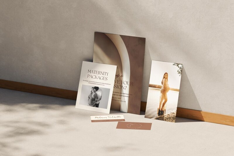 Photography studio marketing materials including maternity packages brochure and portrait prints leaning against a wall in soft daylight.